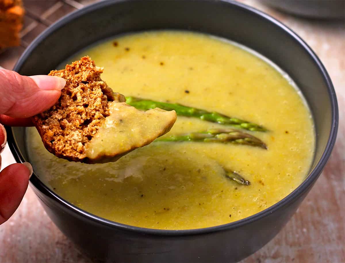 Bread is dipped in creamy asparagus soup.