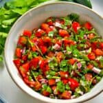 A bowl of pico de gallo with diced tomatoes, onions, cilantro, and jalapenos.