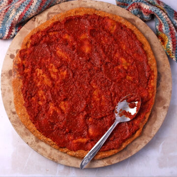 A baked sweet potato pizza crust with tomato sauce.