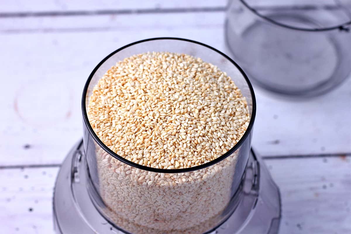 Toasted sesame seeds are added to a small food processor.