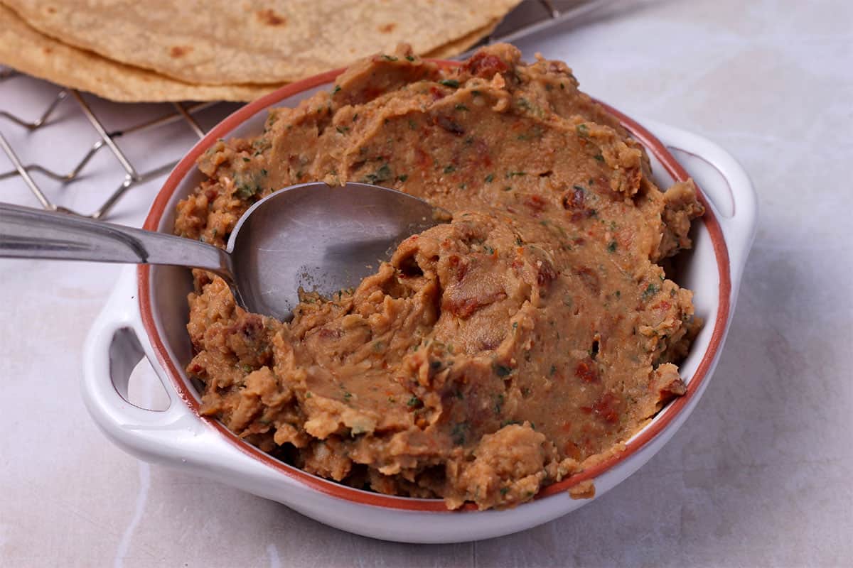 White bean and sun-dried tomato spread in a white bowl with a spoon.