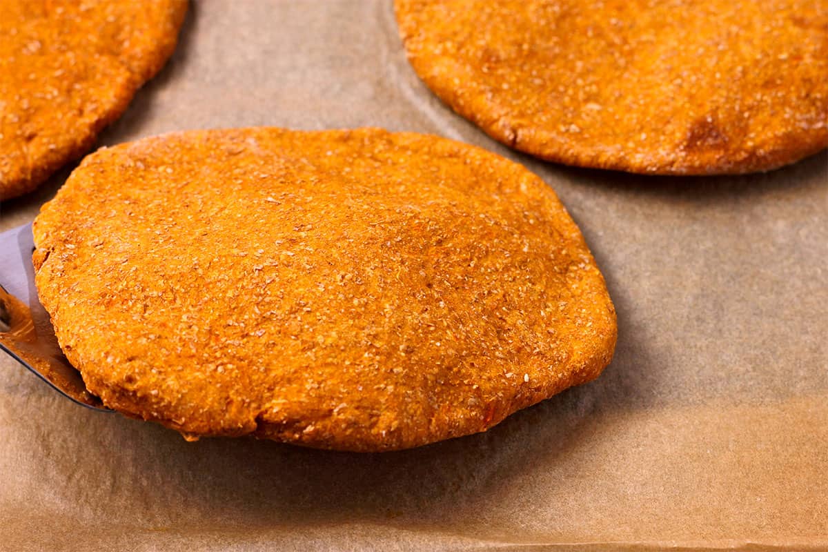 A sweet potato flatbread is flipped with a spatula.