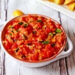 Tomato chutney with onions and basil in a bowl.