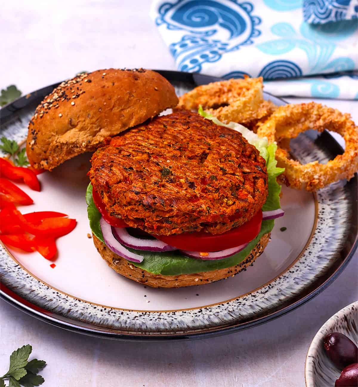 Mediterranean sweet potato and chickpea burger is open-face on a bun.