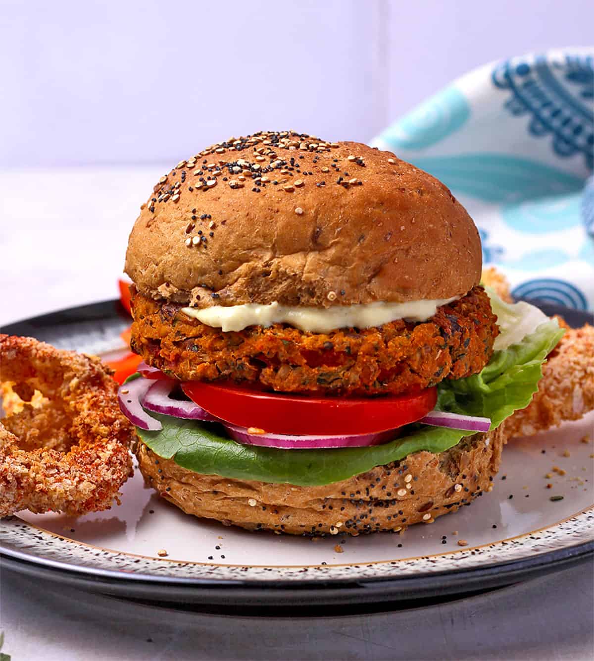 A Mediterranean sweet potato and chickpea burger on a bun with vegan mayo.