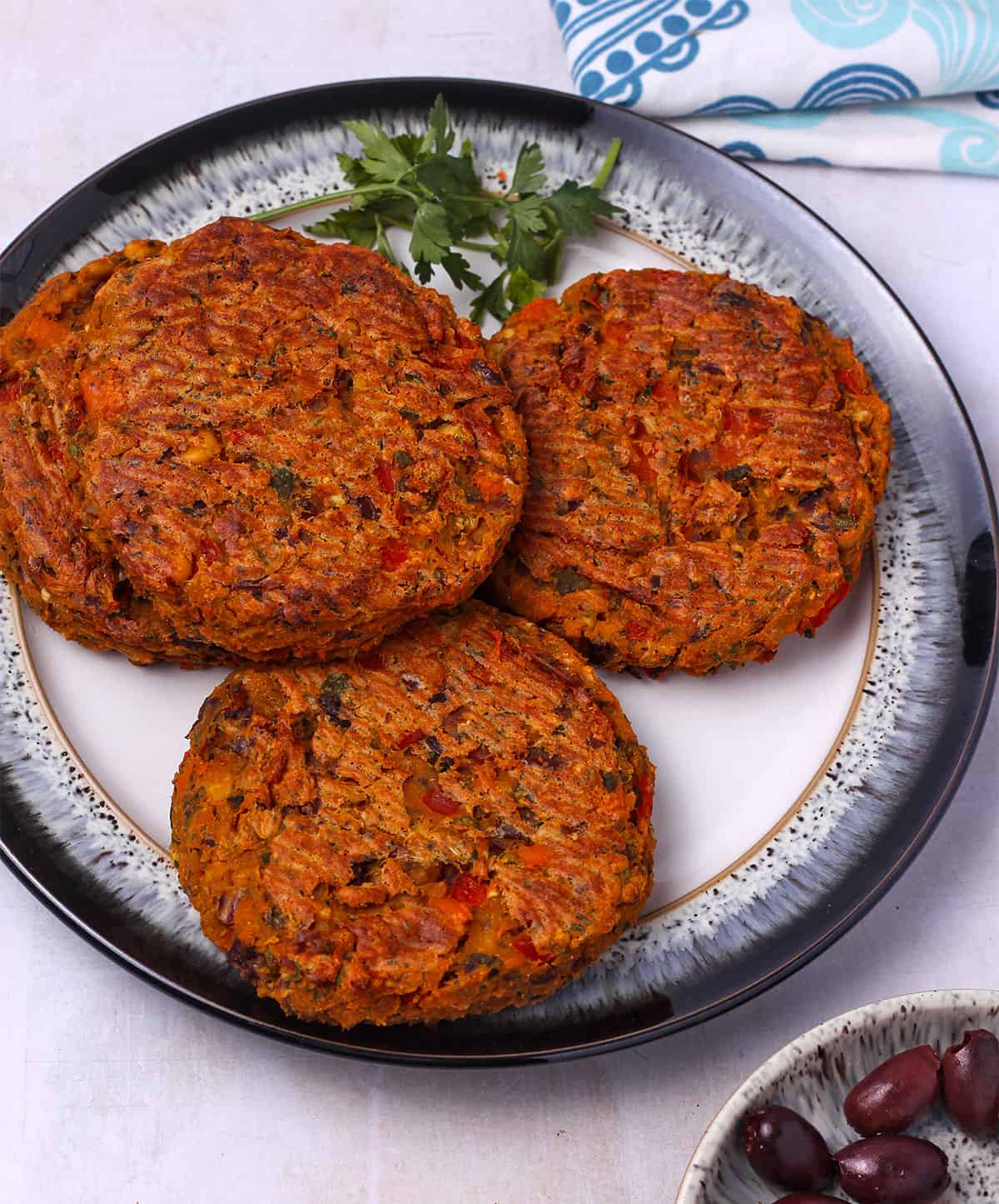 A plate with four sweet potato and chickpea burger patties.