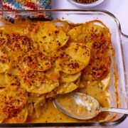 Vegan scalloped potatoes with bacon bits in a casserole dish.
