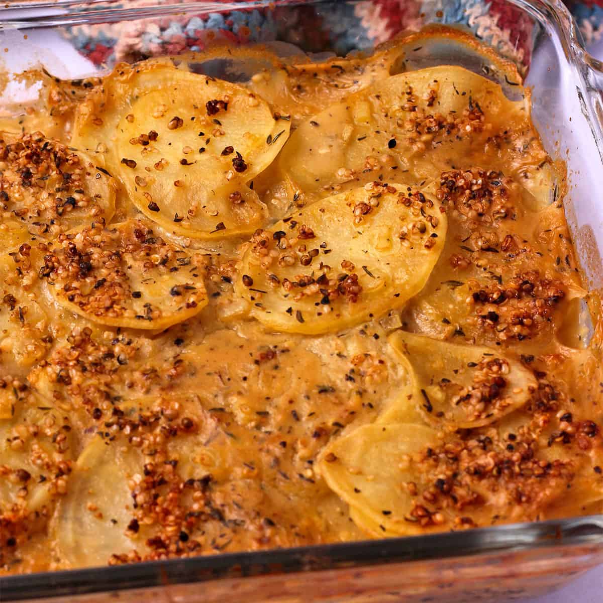 Vegan scalloped potatoes with bacon bits in a baking dish.
