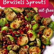 Air fried brussels sprouts with pomegranate seeds and walnuts in a white bowl.