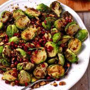 A bowl of roasted brussels sprouts with pomegranate seeds and walnuts.