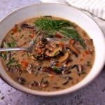 Wild rice mushroom soup with fresh chives and dill in a bowl with a spoon.