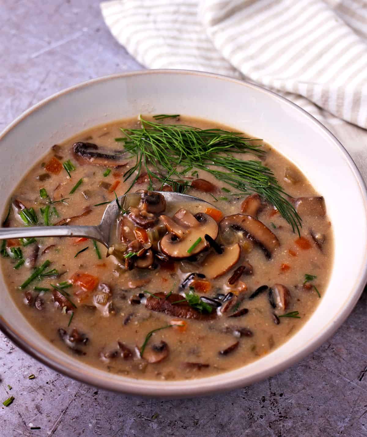 A spoon lifts wild rice mushroom soup from a bowl.