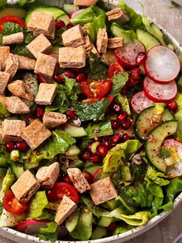 Fattoush salad with pita chips, pomegranate seeds, lettuce, tomatoes, peppers, and radishes.