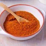 Ground Thai curry powder in a white dish with a wooden spoon.