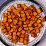 Overhead view of crispy air fryer tofu cubes on a plate.