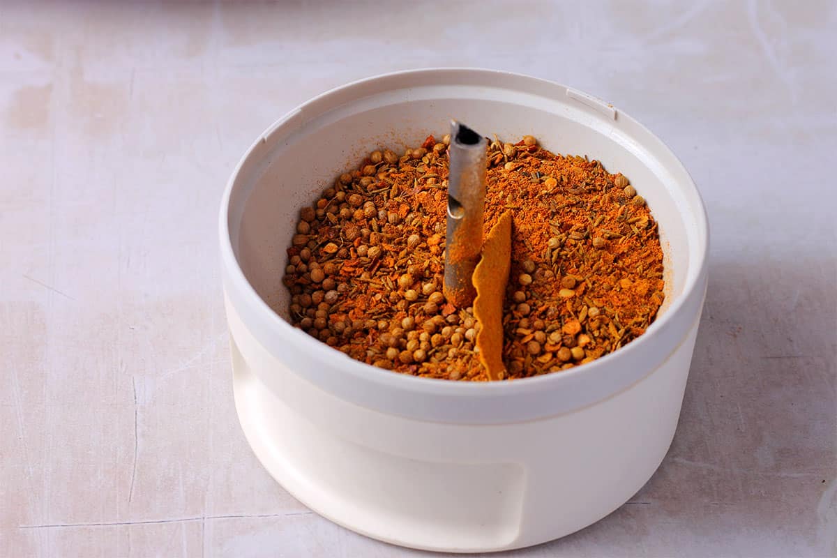 Thai curry powder ingredients are placed in a spice grinder.