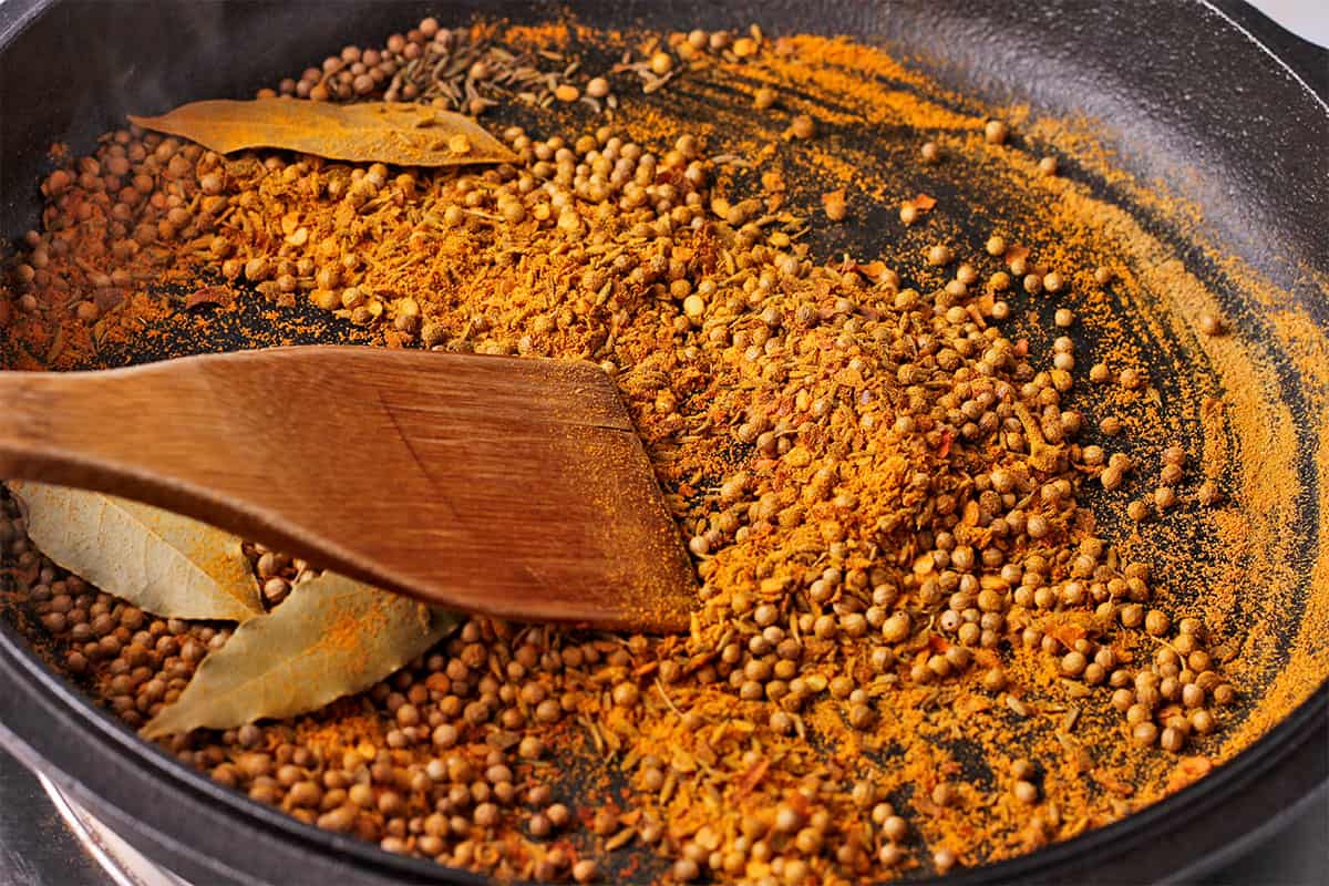 Spices are toasted in a cast iron pan.