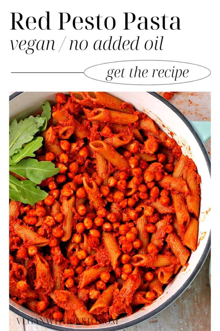 A pot filled with cooked pasta, red pesto, and chickpeas.