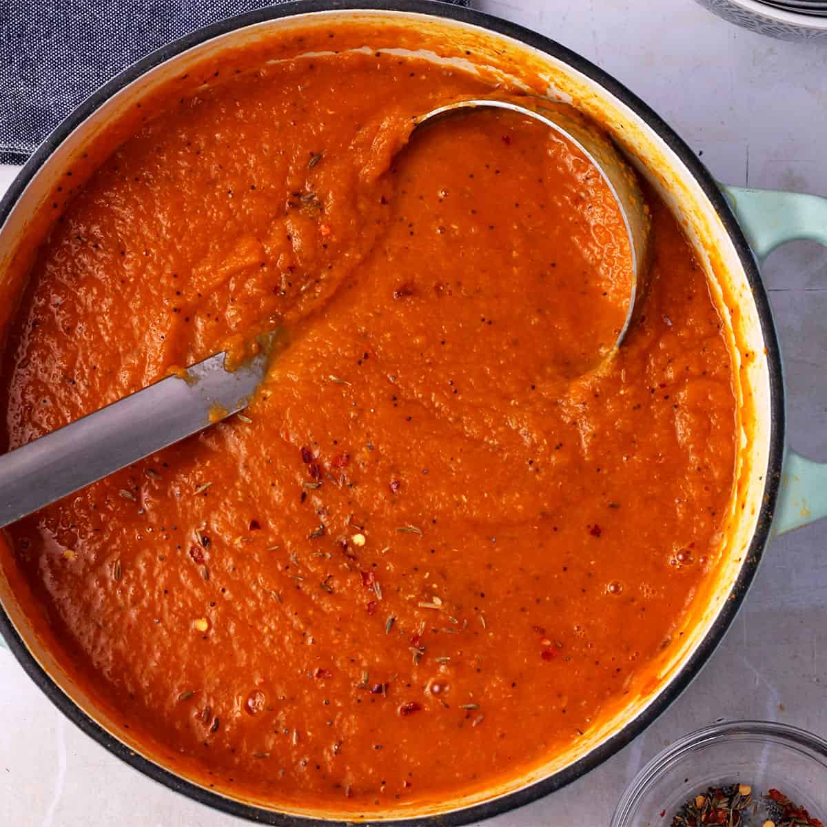 Blended carrot lentil soup in pot with ladle.