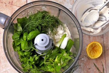 Fresh herbs, scallions, and sour cream in a food processor.