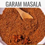 Garam masala in a dish with star anise and a small wooden spoon.