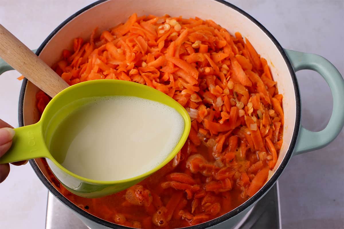 Plant milk is added to shredded carrots, red lentils, and vegetable broth.