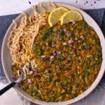 Red lentil and spinach curry in a bowl with noodles.
