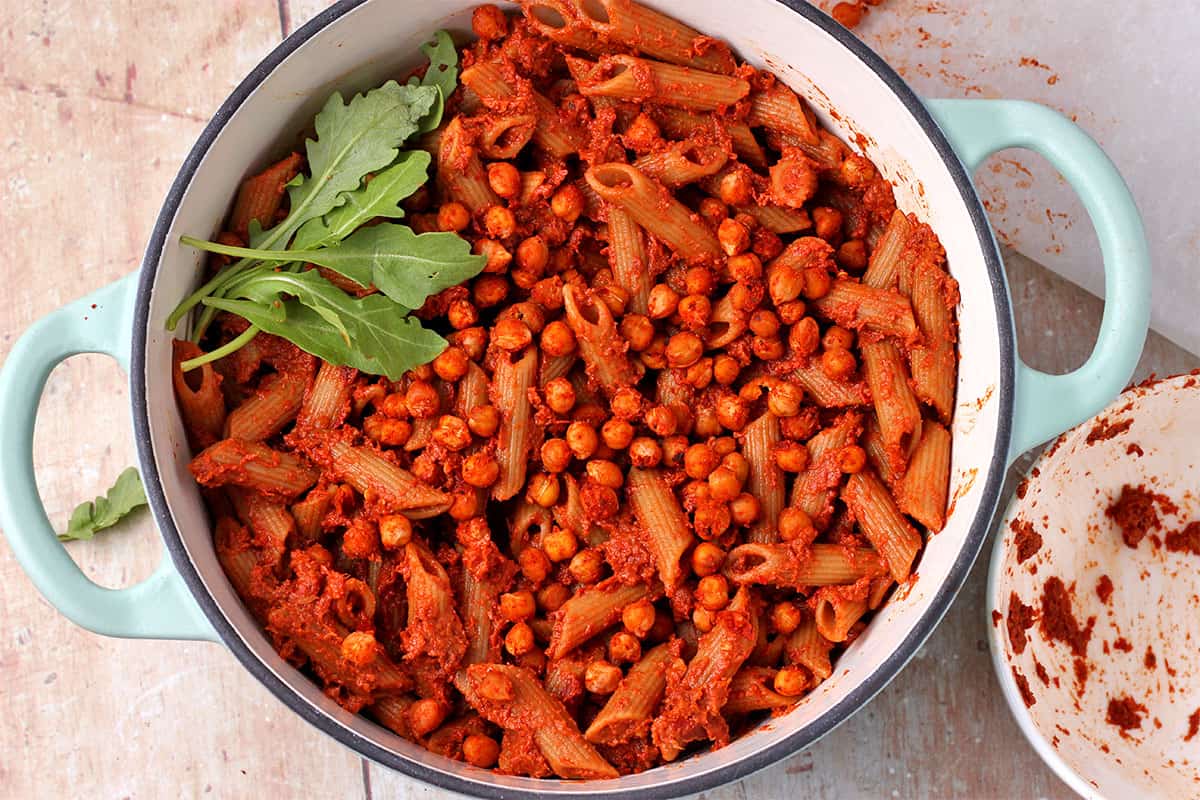Red pesto pasta with chickpeas in a blue pot.