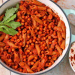 Red pesto pasta with chickpeas and arugula on top.