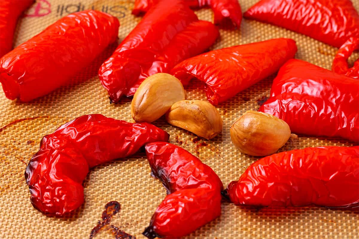 Roasted red peppers and garlic on a baking mat.