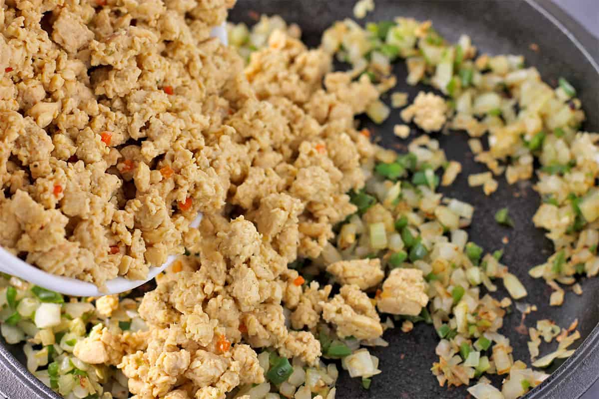 Simmered tempeh crumbles are added to cooked onions and jalapenos.