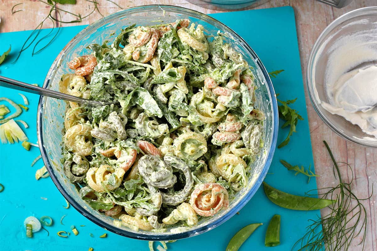 Pasta salad with green goddess dressing in a glass bowl with a spoon.