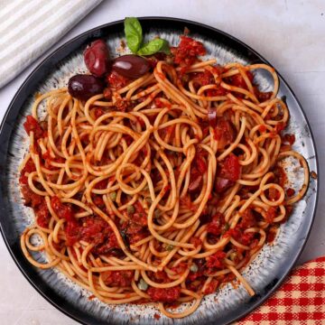Spaghetti puttanesca with olives and capers on a plate.