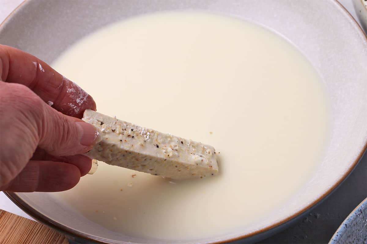 Tofu with cornstarch is dipped into plant milk.