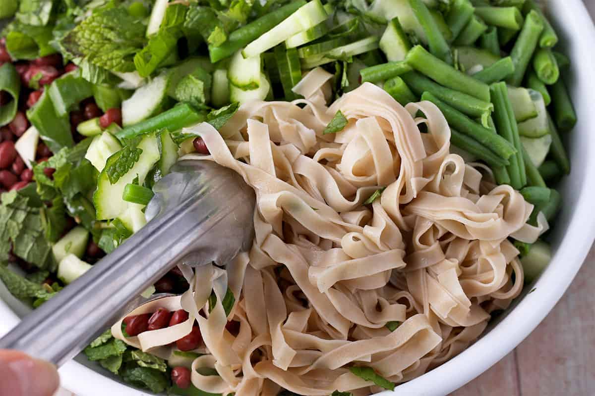 Cooked rice noodles are added to a salad with adzuki beans.