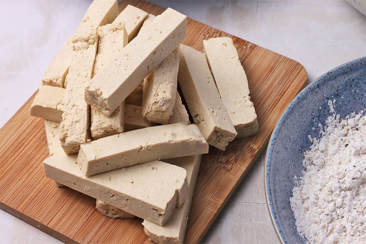 A block of tofu is sliced into rectangular pieces.