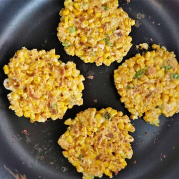 4 corn fritters cooked in a skillet.