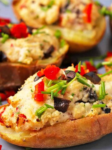 Vegan twice baked potato with chives, olives, and chopped red chili.