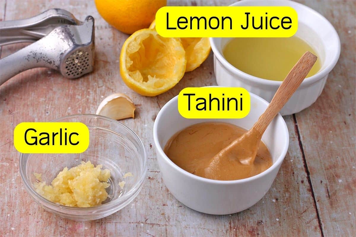 The ingredients for lemon tahini dressing with labels in yellow.