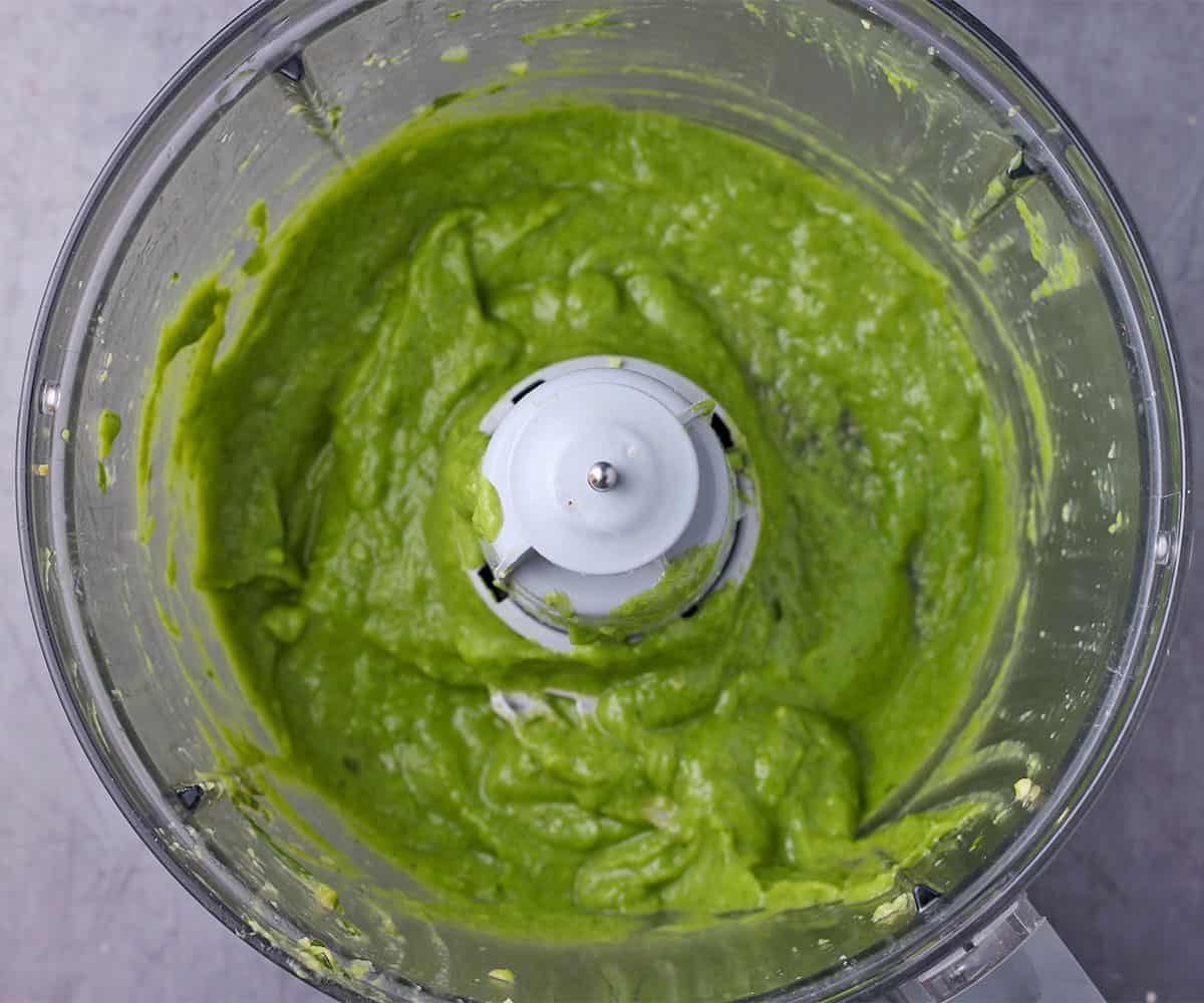 Avocado dressing in blended in a food processor.