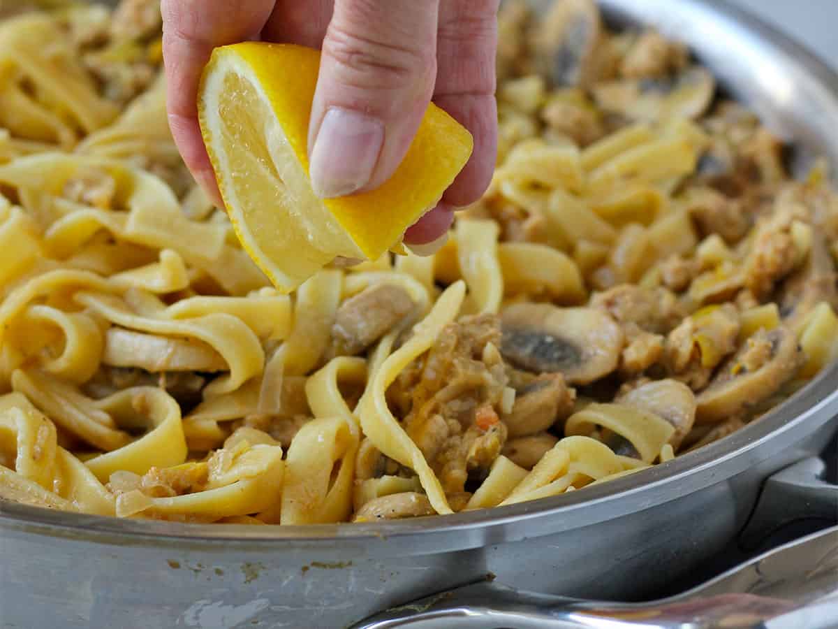 Fresh lemon is squeezed over mushroom stroganoff with pasta.