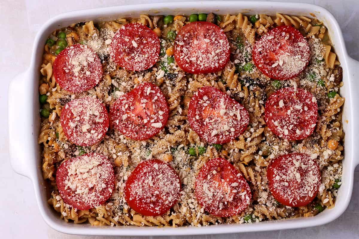 A casserole with pasta is topped with sliced tomatoes and breadcrumbs.