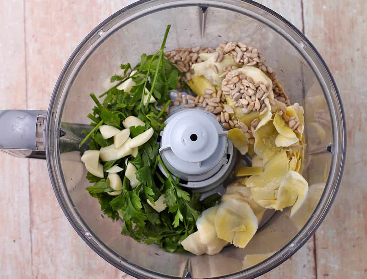 Artichoke hearts, garlic, parsley, and sunflower seeds in a food processor.