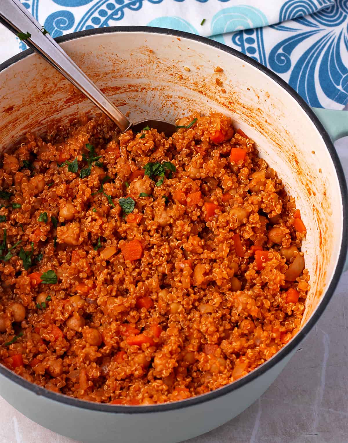 Quinoa pilaf with carrots and chickpeas in a pot with chopped parsley.