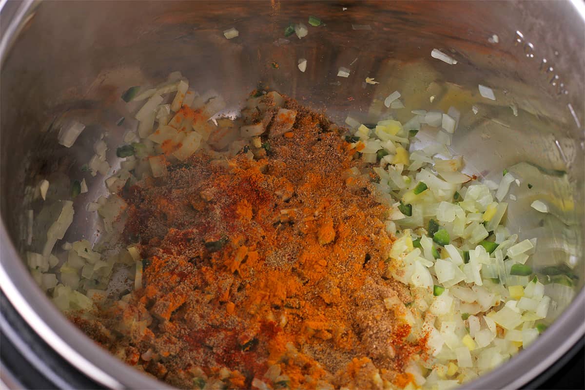 Ground spices are added to onions and jalapenos in the Instant Pot.