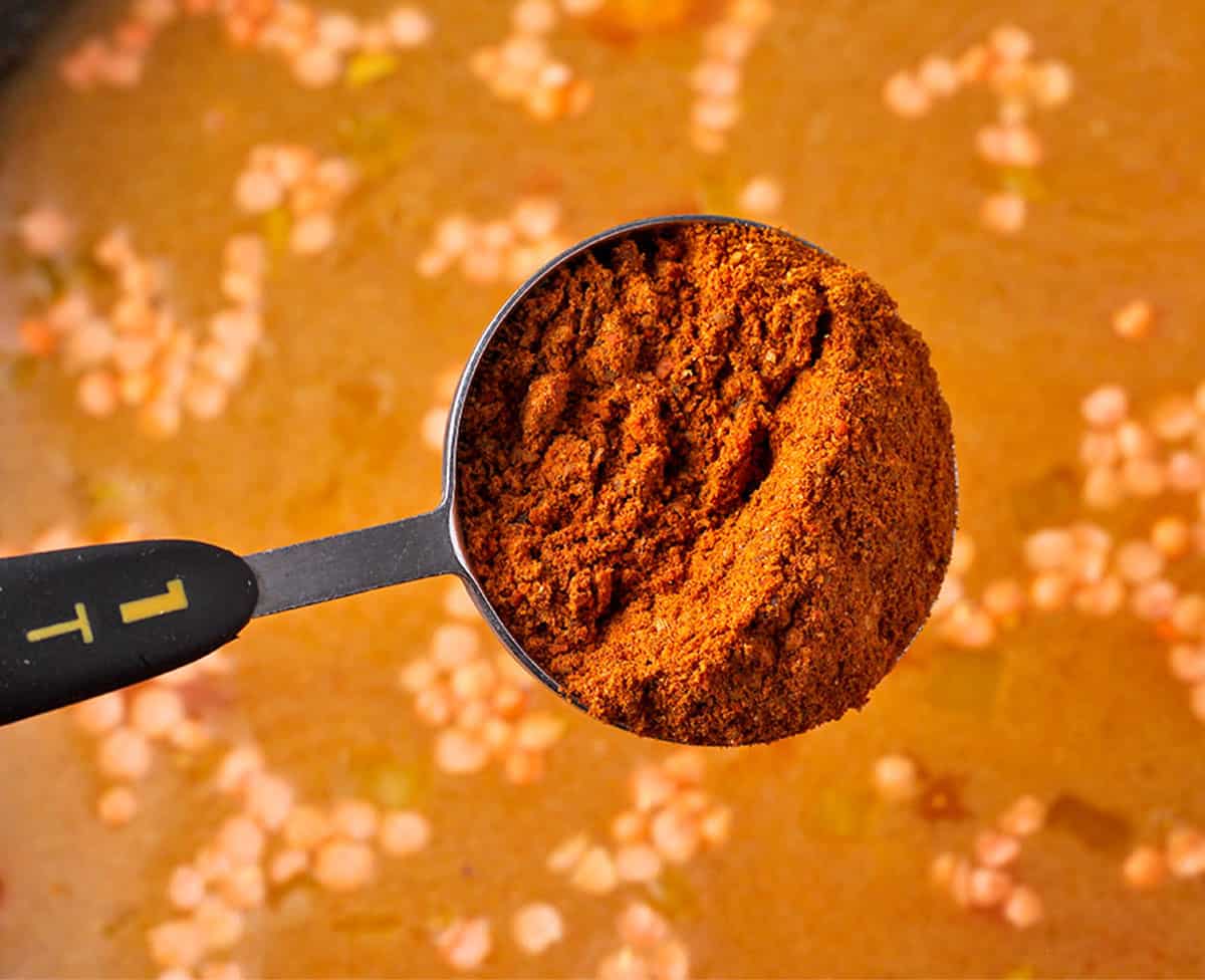 A tablespoon of berbere spice over a pot.