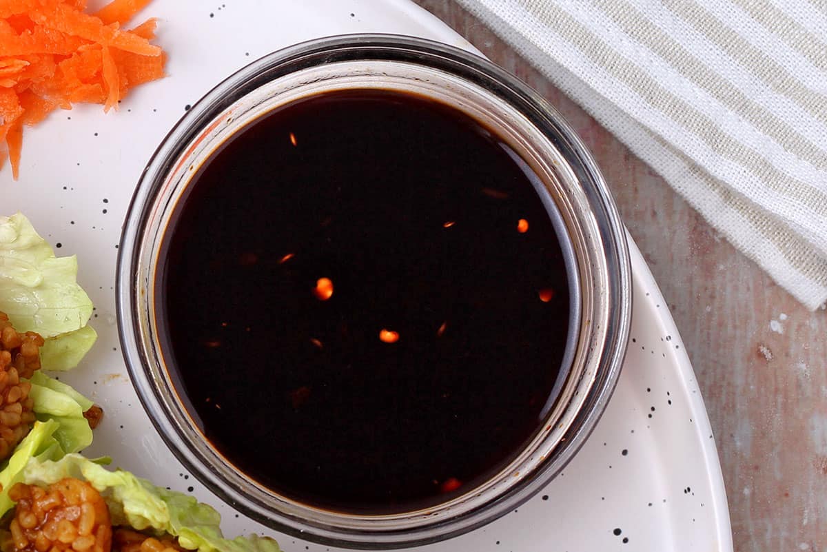 Dipping sauce with soy sauce and red chili flakes in a small glass bowl.