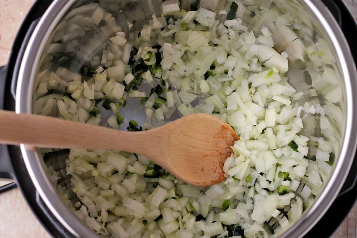 Onions and jalapenos are stirred in the Instant Pot.