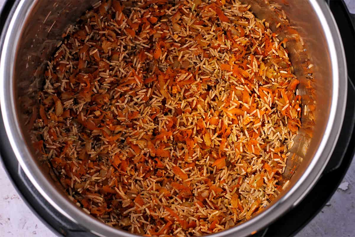 Rice, carrots, onions, and spices in Instant Pot.