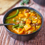 A bowl of bean stew with corn and sweet potatoes.